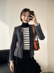 Woman wearing a stylish black and white striped blouse with a patterned jacket and holding a bag.