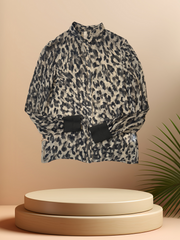 Marccain Silk Leopard Print Shirt displayed on a pedestal with palm leaves, showcasing its chic design and quality fabric.