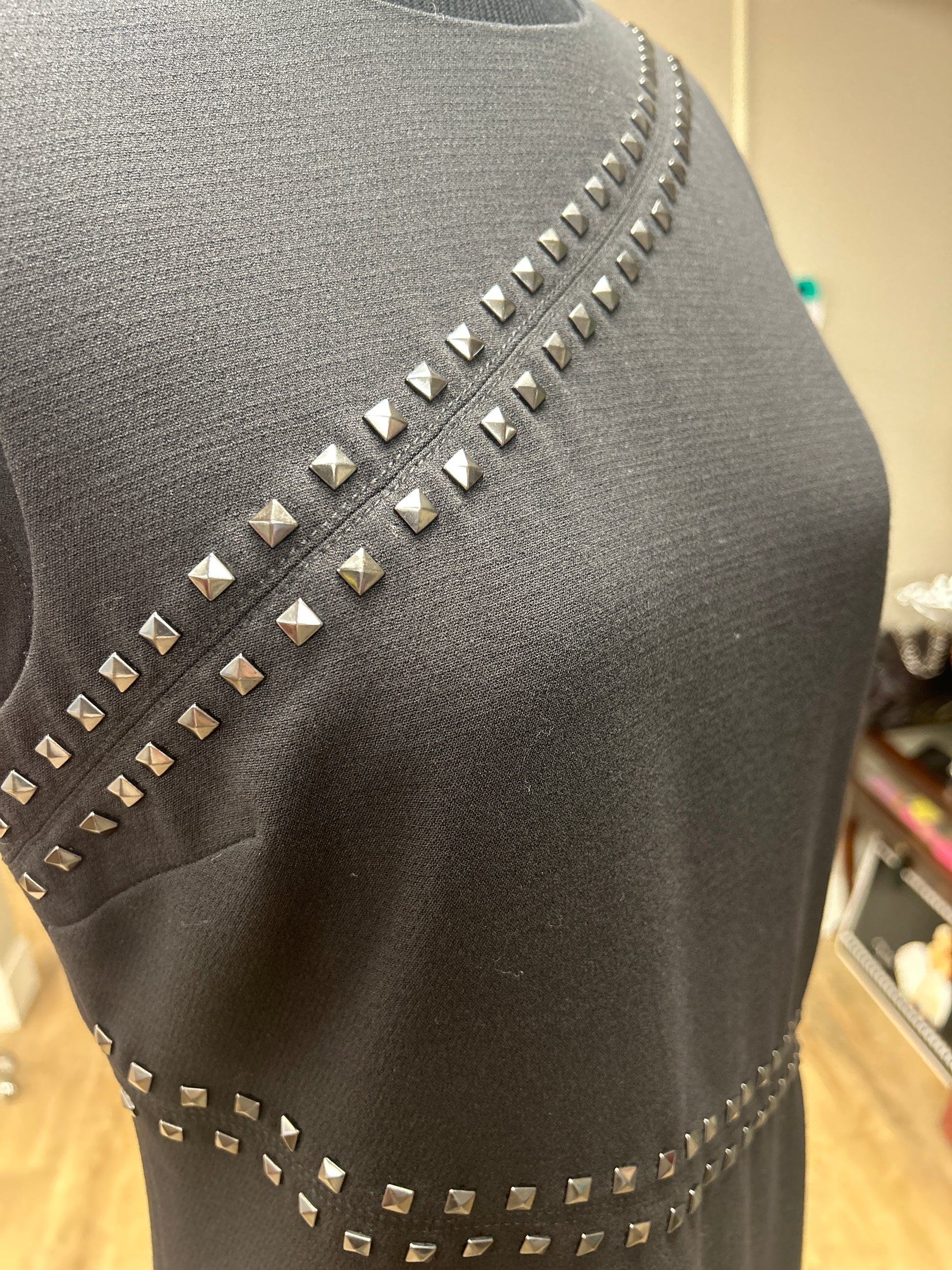Close-up of the Michael Kors Rivet Dress showcasing rivet decoration on a classic black fabric.