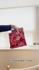 Hand holding a Marccain pink floral print bag, showcasing its stylish design and vibrant rose pattern.