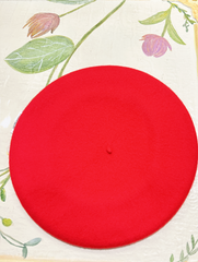 Red wool beret on a floral background, showcasing premium quality and stylish design.
