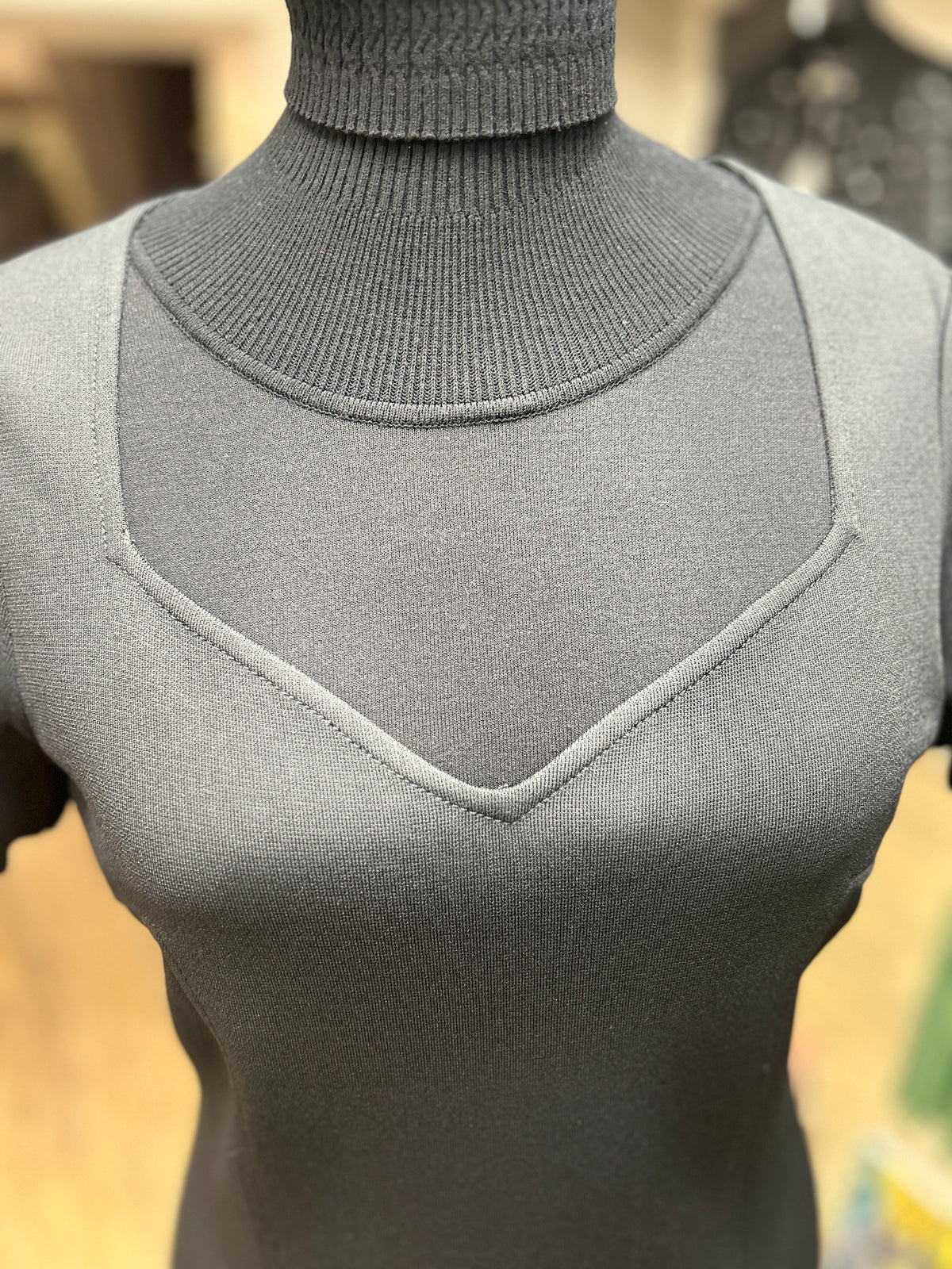 Close-up of a stylish dark grey dress featuring a turtleneck and unique neckline design for an elegant look.