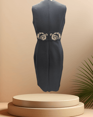 Versace black dress with golden logo and embellishments, exuding elegance and class, displayed on a pedestal.